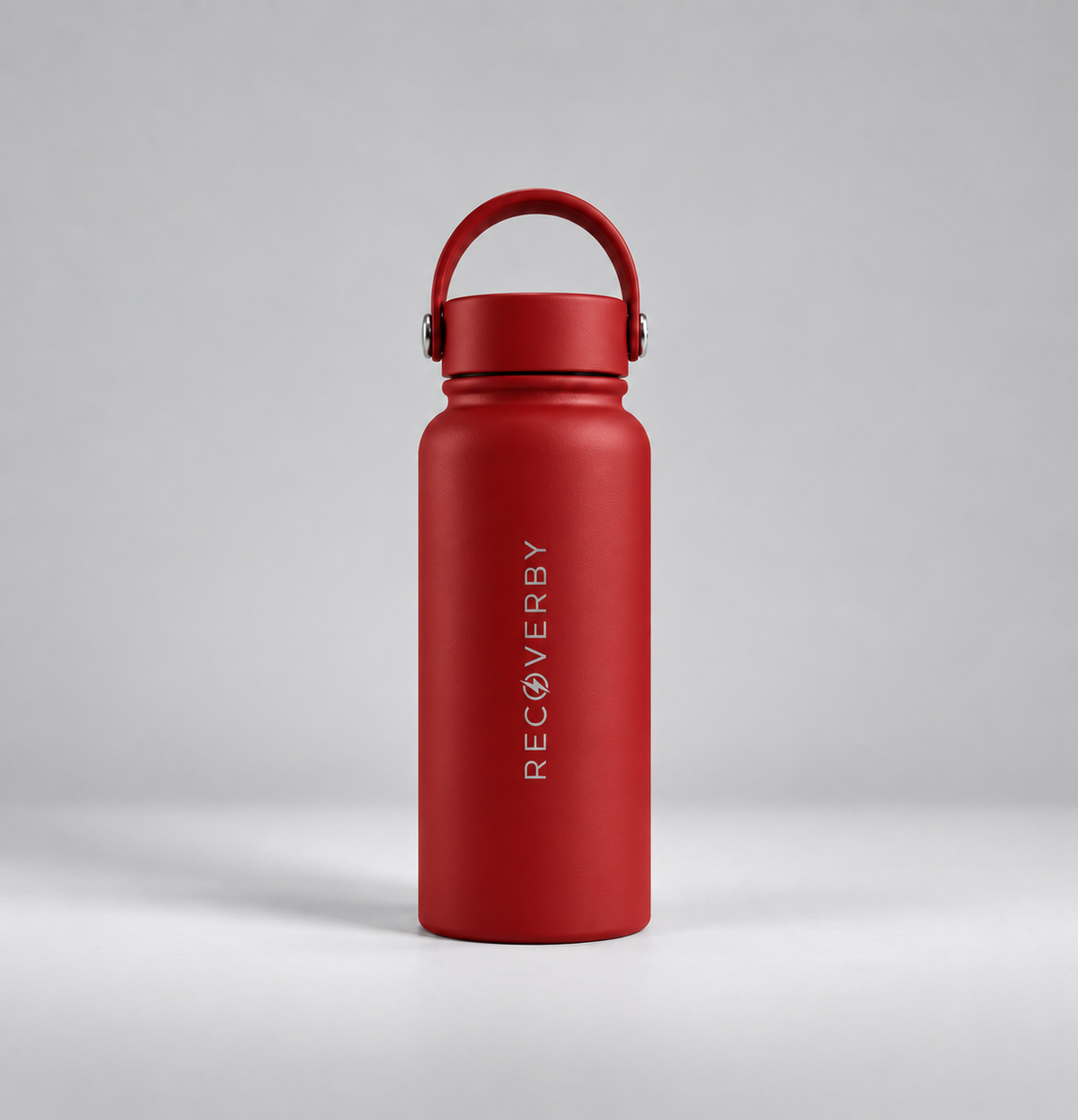A matte red insulated water bottle with a matching red loop handle on the lid, standing upright on a light gray studio background. The brand name 'RECOVERBY' is printed vertically in white on the front.